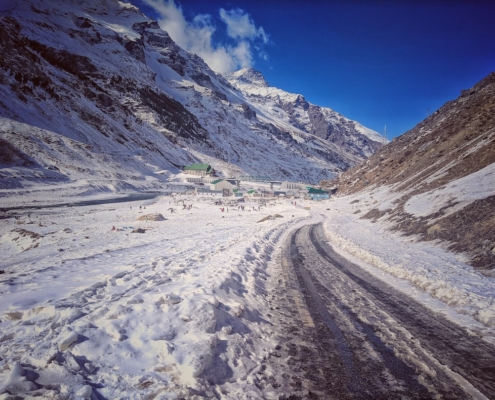 a snow covered road with a mountain in the background
