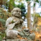 a statue of a man sitting in the middle of a forest