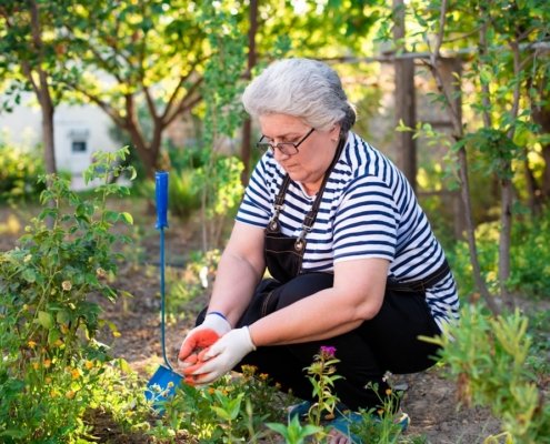 a woman kneeling down in a garden holding an apple