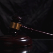 A wooden gavel rests on a dark surface.