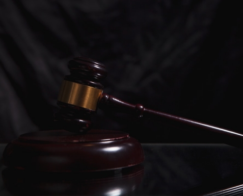 A wooden gavel rests on a dark surface.
