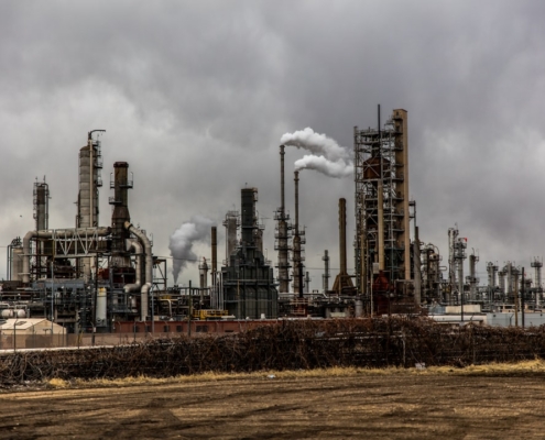 factories with smoke under cloudy sky