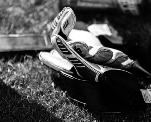 greyscale photo pair of gloves on grass field
