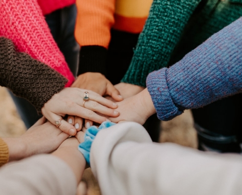 group stacking hands in colorful sweaters
