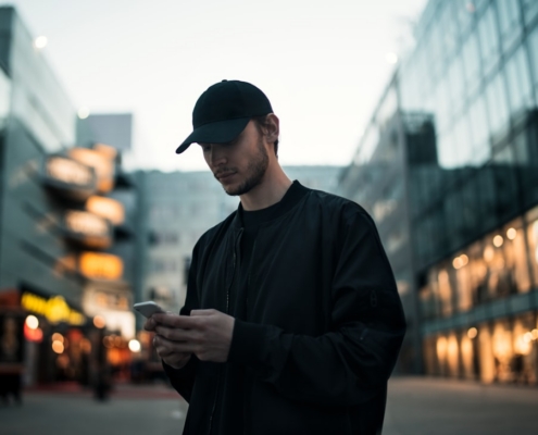 man in black jacket wearing black fitted cap while using phone