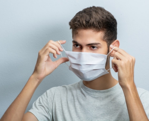 man in gray crew neck t-shirt covering his face with white textile