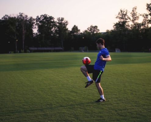 man juggling ball on grass field