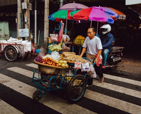 man pushing his food cart on pedestrian lane during daytime