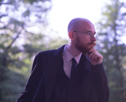 man wearing black coat holding his chin