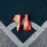 pair of orange adidas cleats on gray surface