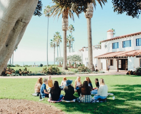 people sitting on ground while forming round during daytime