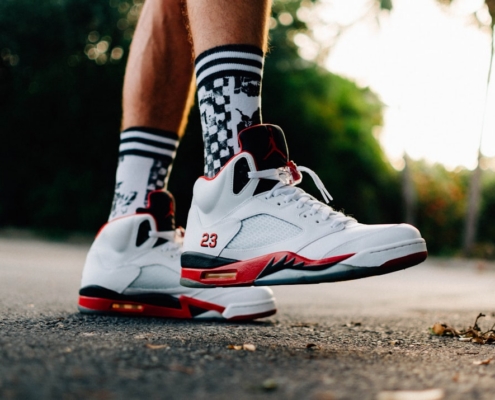 person wearing white-black-and-orange Air Jordan 5 shoes