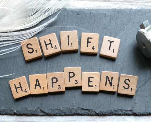 scrabble chips forming shift happens word near white feather