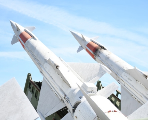 Two white missiles pointed upwards against blue sky