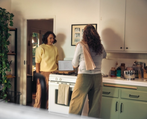 Two women talking in a kitchen while cooking