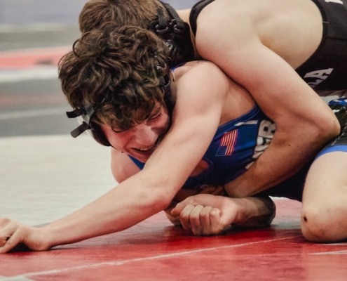 Two wrestlers grappling intensely on a mat