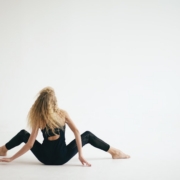 Woman in black jumpsuit sitting on white floor