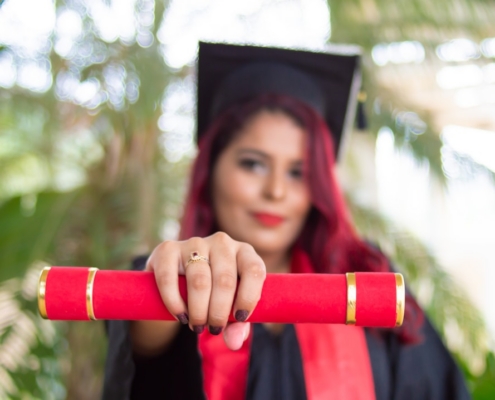 woman in red long sleeve shirt holding red and black academic hat