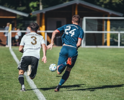 2 men playing soccer on green grass field during daytime