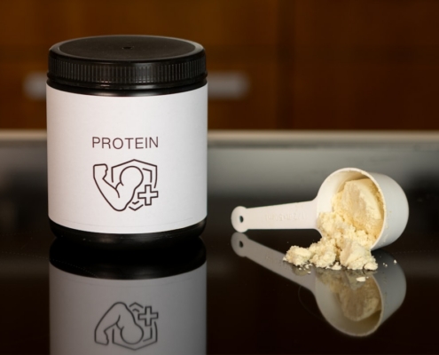 a container of protein powder next to a spoon