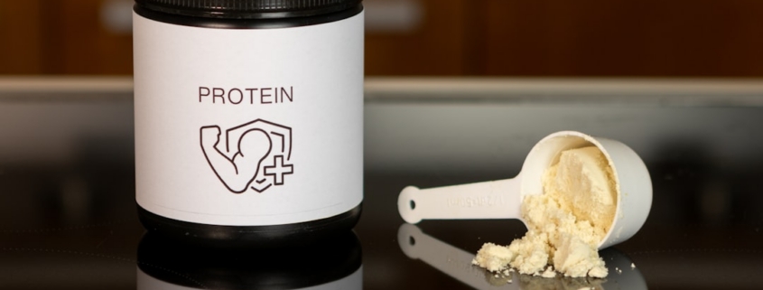 a container of protein powder next to a spoon