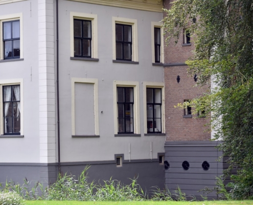 A large white house sitting next to a lush green park