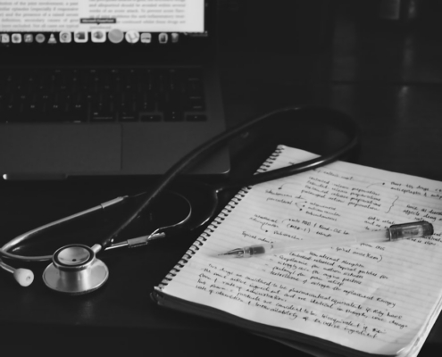 a notebook with a stethoscope on top of it next to a laptop
