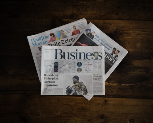 a stack of newspapers sitting on top of a wooden table