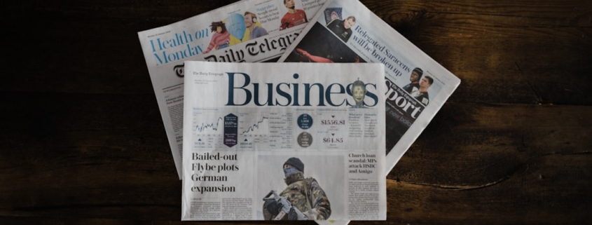 a stack of newspapers sitting on top of a wooden table