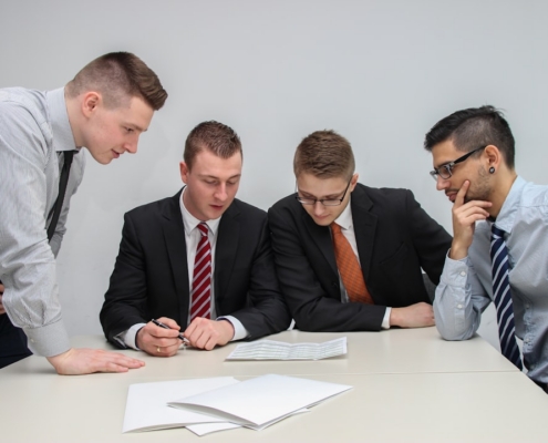four men looking to the paper on table