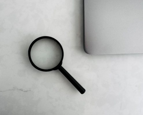 Magnifying glass sits near a laptop on a table.