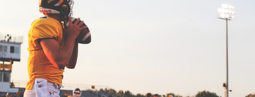 man holding brown football ball