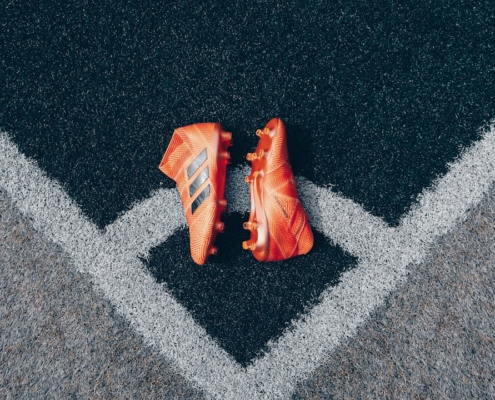 pair of orange adidas cleats on gray surface