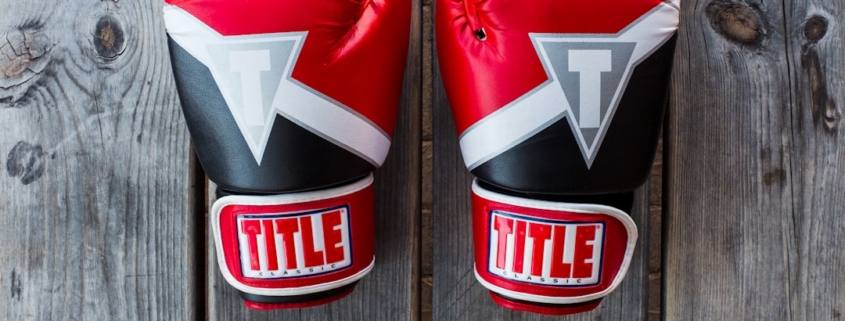 pair of red-and-black Title training gloves on grey wooden plank