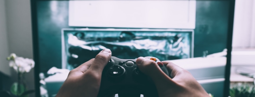 person holding game controller in-front of television