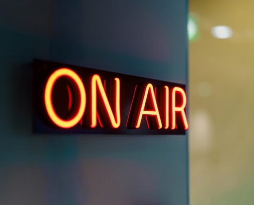 Red neon "on air" sign glowing on wall.