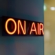 Red neon "on air" sign glowing on wall.