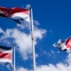 Three national flags waving against a blue sky