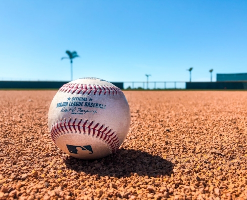 white and red baseball on brown soil during daytime
