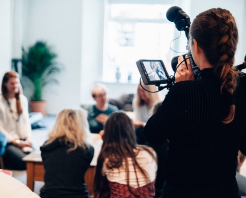 woman holding camera standing near people