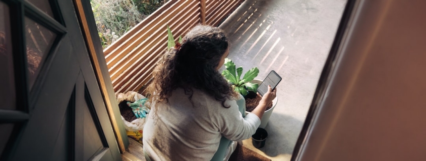 Woman sitting on balcony with smartphone