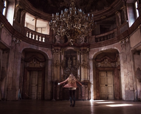 woman standing under gold chandelier indoors